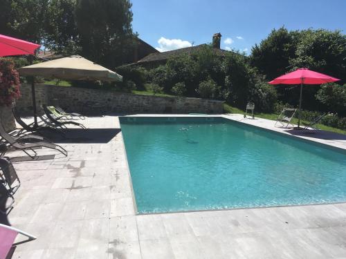 une piscine avec deux chaises et un parasol dans l'établissement Château de la Chabroulie, à Isle