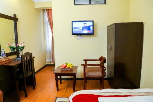 a room with a bed and a table and a television at Thamel Home in Kathmandu