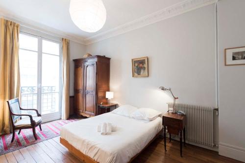 une chambre avec un lit, une chaise et une fenêtre dans l'établissement Veeve - Tranquility by Le Jardin du Luxembourg, à Paris