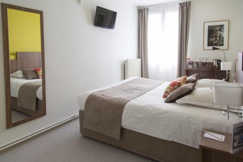 a bedroom with a large bed and a mirror at Logis Hôtel Chaptal, Amboise in Amboise