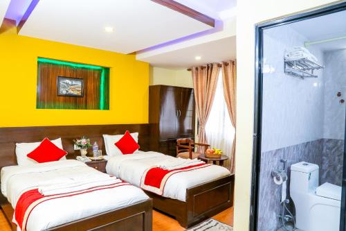 two beds in a hotel room with yellow walls at Thamel Home in Kathmandu