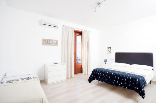 a white bedroom with two beds and a window at Il Vicolo B&B in Milazzo