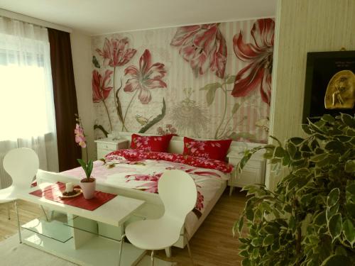 a bedroom with a bed with red pillows and a floral wallpaper at Ferienhaus Kramser in Arnoldstein