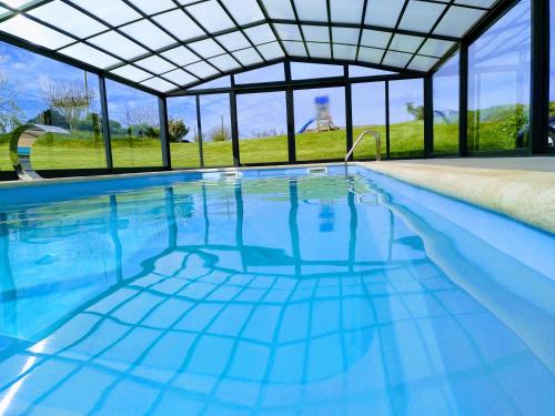 an indoor swimming pool with a glass ceiling and blue water at Hotel La Casa Del Abuelo in Tapia de Casariego