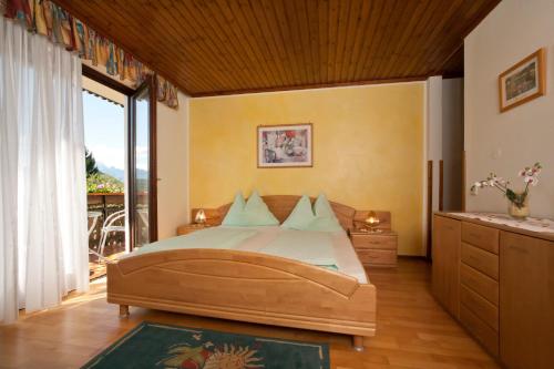 a bedroom with a large bed and a balcony at Pension Windinger in Schiefling am See