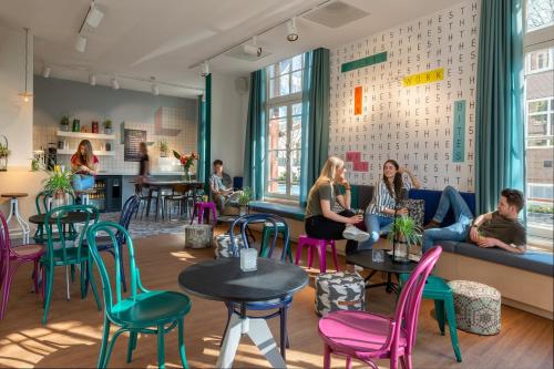 a group of people sitting in a room with tables and chairs at Stayokay Hostel Amsterdam Vondelpark in Amsterdam
