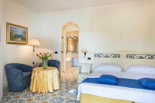 a bedroom with a bed and a table with a vase of flowers at Hotel Hermitage in Portoferraio