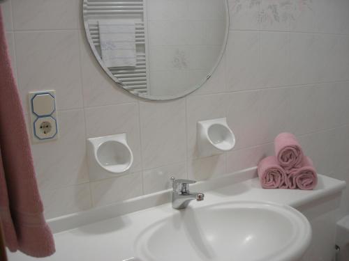 a bathroom with a sink and a mirror and pink towels at Appartments Helvetia in Villabassa