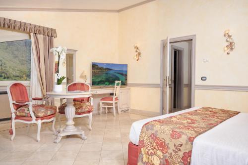 a bedroom with a bed and a table and chairs at Hotel Hermitage in Portoferraio