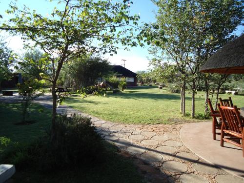a garden with two wooden chairs and an umbrella at Phokoje Bush Lodge in Selebi-Pikwe