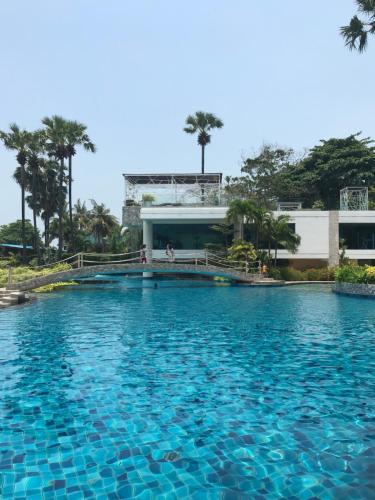 une grande piscine d'eau bleue devant un bâtiment dans l'établissement The palm wongamat pattaya, à Pattaya (nord)