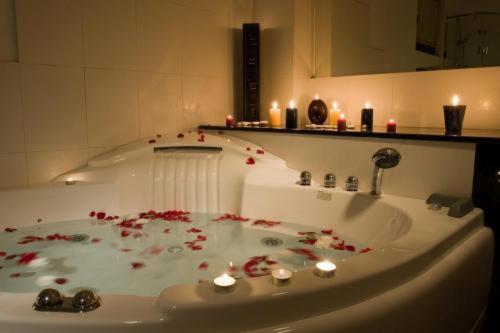 La salle de bains est pourvue d'une baignoire avec des fleurs rouges. dans l'établissement Hotel Orphey, à Bansko