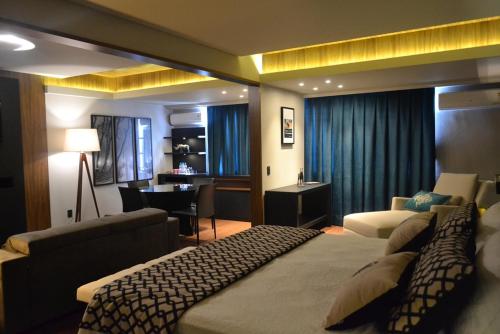 a hotel room with two beds and a living room at Premium Vila Velha Hotel in Ponta Grossa