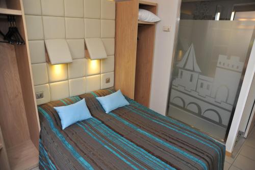 a bedroom with a bed with two blue pillows at Hotel Espace Cite in Carcassonne