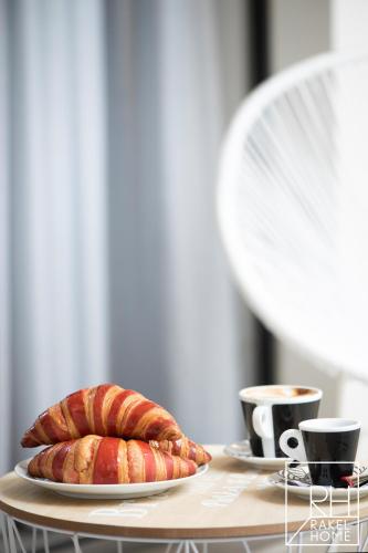 a table with two plates of croissants and cups of coffee at B&B Rakel Home in Milazzo