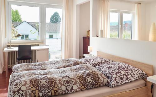 a bedroom with a bed and a desk and windows at Apartment in musikalischem Haus in Mayen