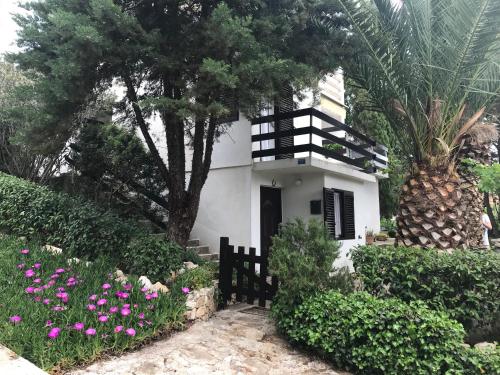 una casa blanca con flores rosas y una valla en Apartment Lavanda en Molat