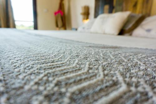 a close up of a bed with a gray blanket at Maria Del Mar Tulum - Adults Only in Tulum