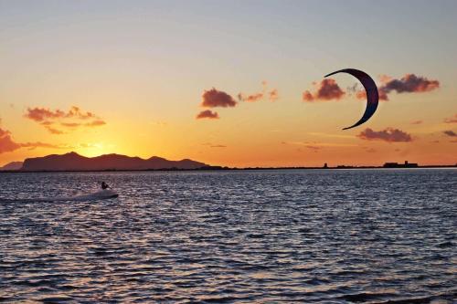 a person flying a kite in the water at sunset at Giulietta b&b in Marsala