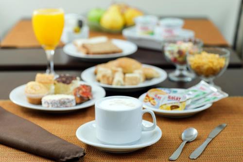a table with plates of breakfast foods and a cup of orange juice at Grand Hotel in Reconquista