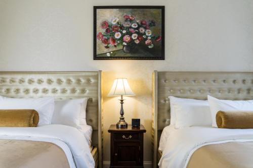 a bedroom with two beds and a painting of flowers at The Mount Vernon Grand Hotel in Mount Vernon