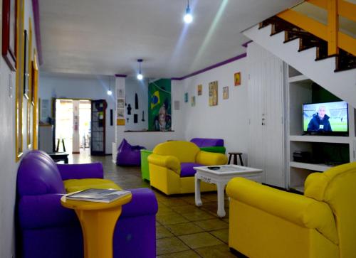 Cabo Frio Fun Hostel في كابو فريو: غرفة معيشة مع كراسي ملونة وتلفزيون