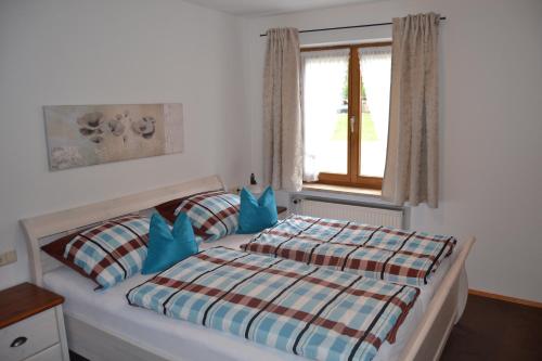 Un dormitorio con una cama con almohadas azules y una ventana en Almwohnung Neuner en Walchensee