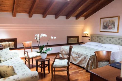 1 dormitorio con 1 cama, mesa y sillas en Phi Hotel Dei Medaglioni en Correggio