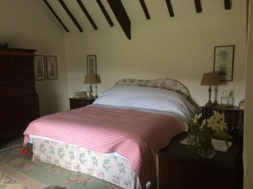 a bedroom with a bed with a pink and white blanket at Barmoors in Lastingham