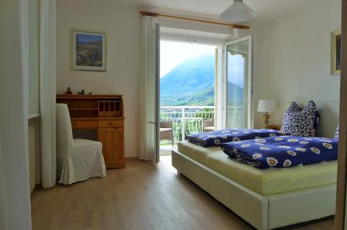 a bedroom with a bed and a desk and a window at Appartement Trafoier in Tirolo