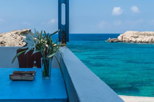 a vase of flowers sitting on a table next to the ocean at Zorbas Studios in Lefkos Karpathou
