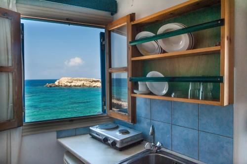 a kitchen with a window with a view of the ocean at Zorbas Studios in Lefkos Karpathou