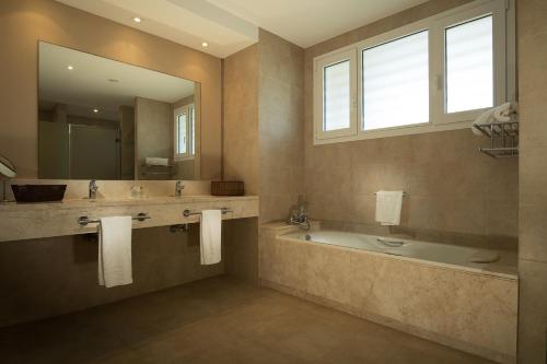 a bathroom with a tub and a sink and a mirror at Suites Puerto Sherry in El Puerto de Santa María