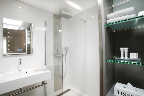a white bathroom with a shower and a sink at Seventeen Hotel in Valbonne