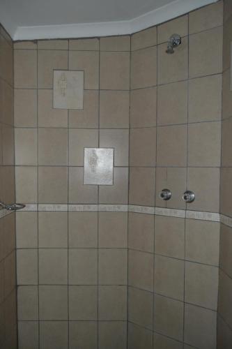 a bathroom with a tiled shower with two stickers at Kenhardt Hotel in Kenhardt