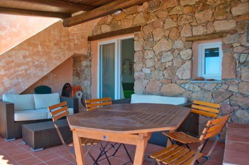 a table and chairs on a patio with a stone wall at Sardegna Isola Rossa La Terrazza panoramiccissimo Cod iun S 8250 in Trinità dʼAgultu