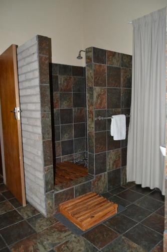 a bathroom with a shower with a stone wall at Kenhardt Hotel in Kenhardt