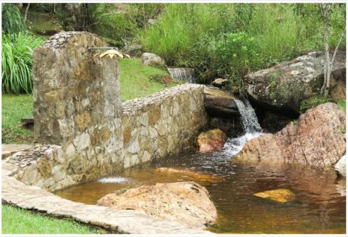 a stone wall next to a small pond with a waterfall at Calcada Sao Jose in Tiradentes