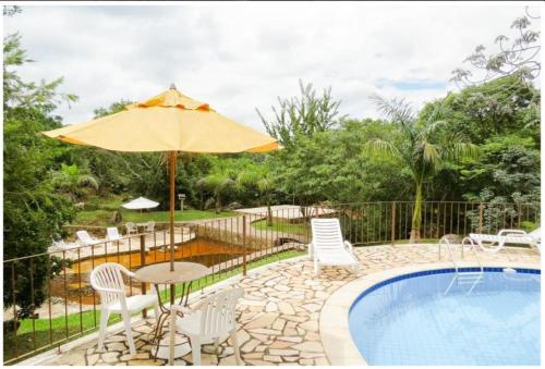 a patio with a table and umbrella next to a pool at Calcada Sao Jose in Tiradentes