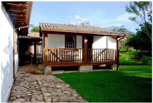 a small house with a porch and green grass at Calcada Sao Jose in Tiradentes