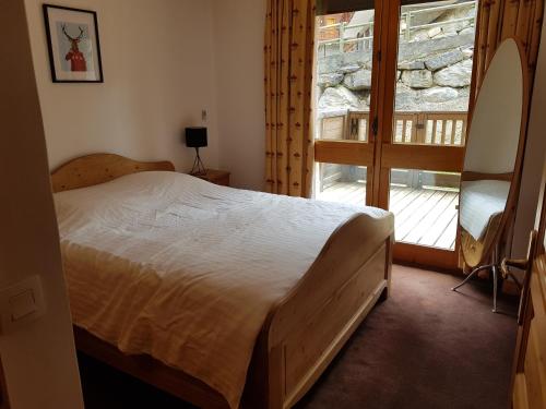 a bedroom with a bed and a large window at Un été à Courchevel in Courchevel