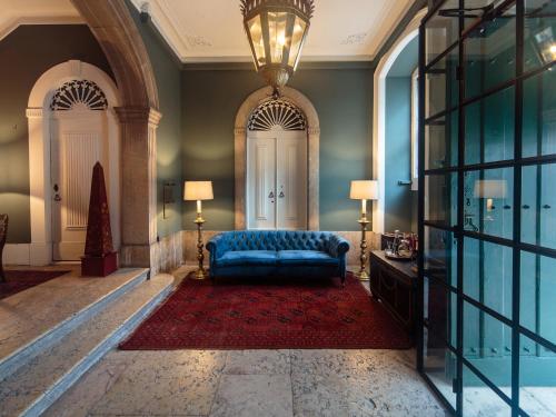 a living room with a blue couch and a chandelier at Dear Lisbon - Bordalo Palace Chiado in Lisbon
