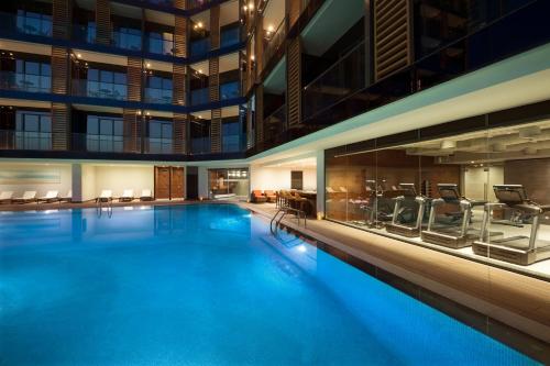 a large swimming pool in a building with chairs at Wyndham Garden Ajman Corniche in Ajman 