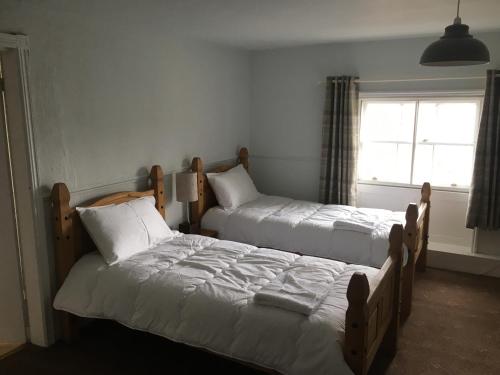 a bedroom with two beds and a window at The Cross Keys Hotel in Llanymynech
