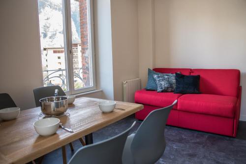 a living room with a red couch and a wooden table at Appart'Hotel Aiguille Verte & Spa in Chamonix-Mont-Blanc
