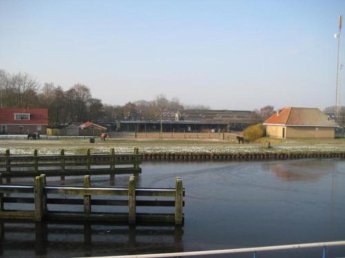 a body of water with a fence and a building at Hotel de Vriezerbrug in Tynaarlo