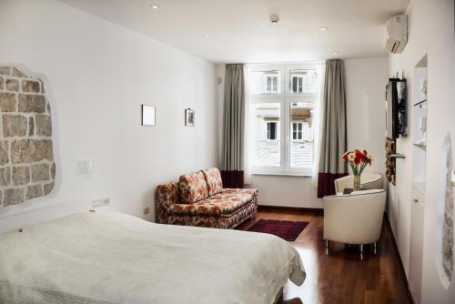 a bedroom with a bed and a chair and a window at Old Square Studio Apartment in Split