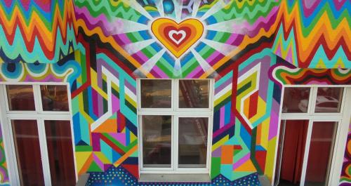 a colorful mural on the side of a building with two windows at Happy Go Lucky Hotel + Hostel in Berlin