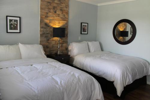 a bedroom with two beds with white sheets and a mirror at Studiotel Bromont in Bromont