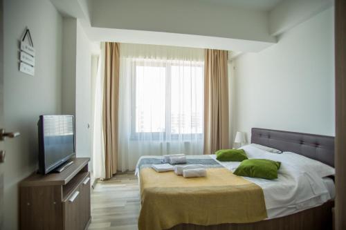 una camera da letto con un letto con cuscini verdi e una TV di Bella Vista Summerland a Mamaia